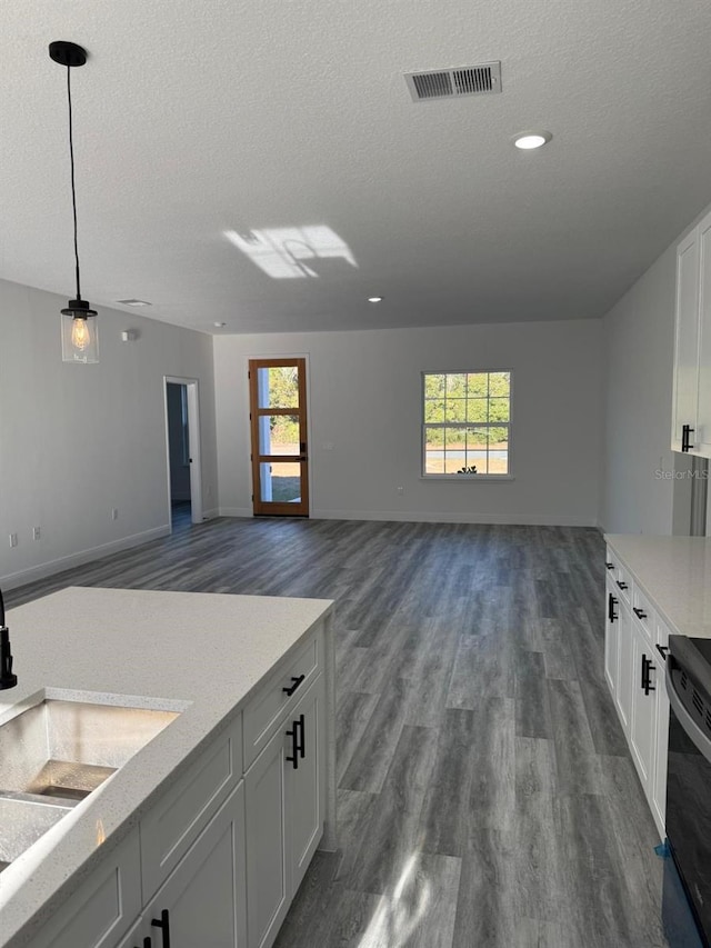 kitchen featuring plenty of natural light, decorative light fixtures, a textured ceiling, white cabinets, and sink