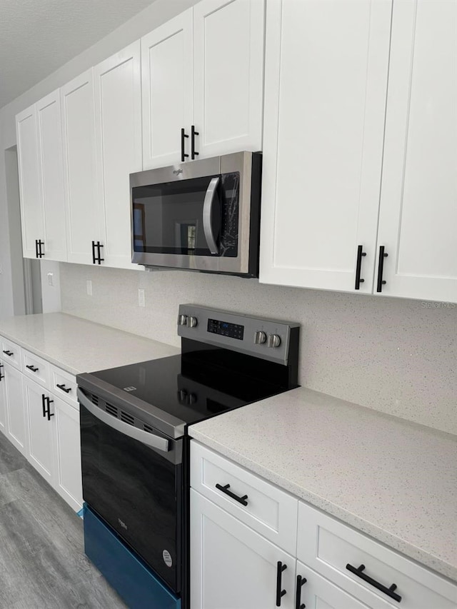 kitchen featuring stainless steel appliances, decorative backsplash, and white cabinetry