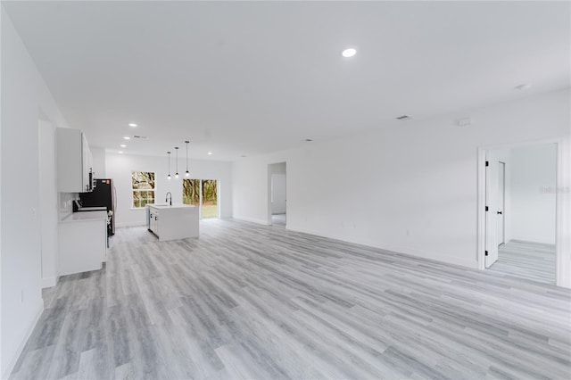 unfurnished living room with light hardwood / wood-style floors and sink