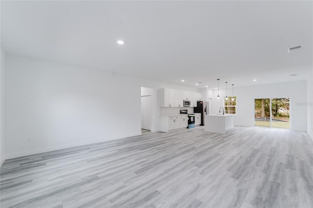 unfurnished living room featuring light hardwood / wood-style flooring and sink