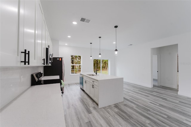 kitchen with hanging light fixtures, stainless steel appliances, white cabinets, a kitchen island, and sink