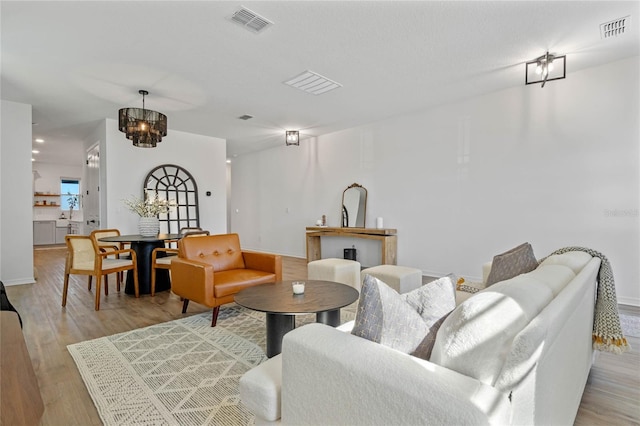 living room featuring a chandelier and light wood-type flooring