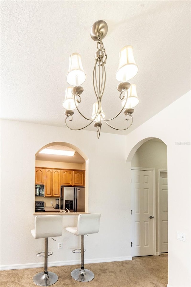 1351 Venezia Ct Unit 304, Davenport, FL 33896 - kitchen with arched walkways, black microwave, light colored carpet, and stainless steel fridge