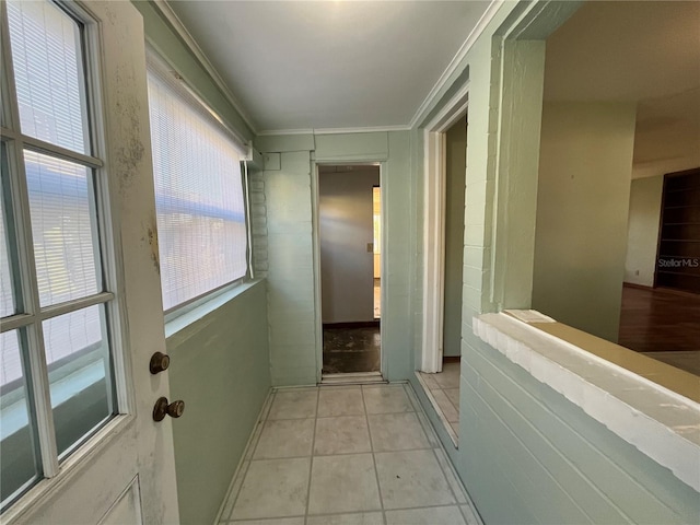 corridor featuring light tile patterned floors, plenty of natural light, and ornamental molding