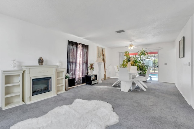 living room with ceiling fan, carpet floors, and a textured ceiling