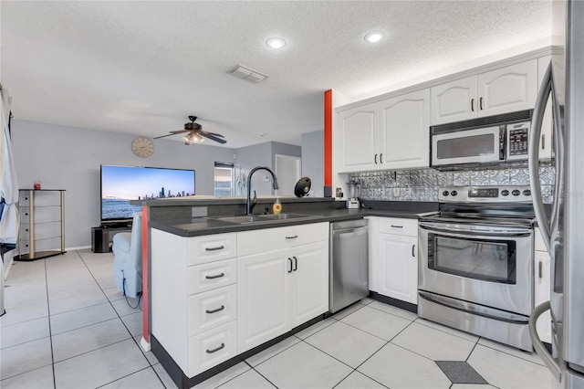 kitchen featuring kitchen peninsula, stainless steel appliances, ceiling fan, sink, and white cabinetry