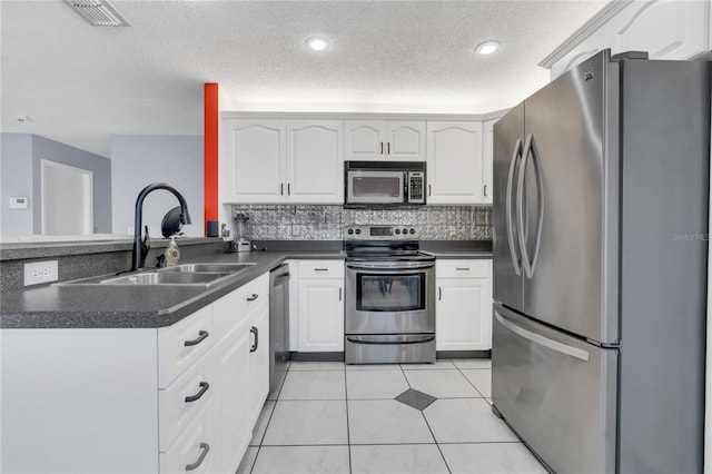 kitchen featuring kitchen peninsula, appliances with stainless steel finishes, sink, light tile patterned floors, and white cabinets