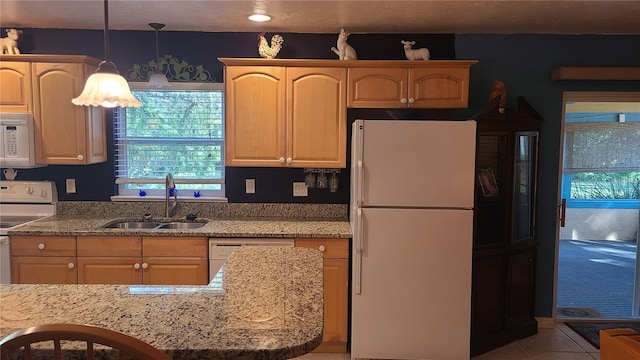 kitchen with light stone countertops, sink, pendant lighting, white appliances, and light tile patterned flooring