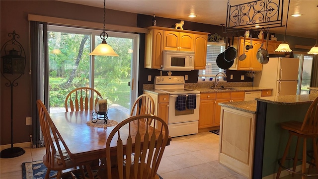 kitchen featuring light stone counters, white appliances, sink, pendant lighting, and light tile patterned flooring