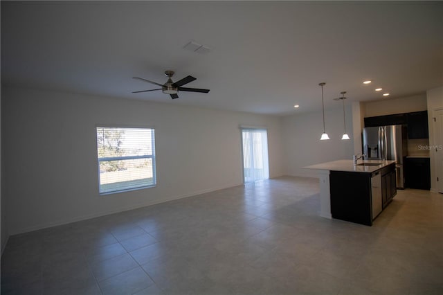 kitchen with ceiling fan, sink, hanging light fixtures, stainless steel fridge with ice dispenser, and a center island with sink