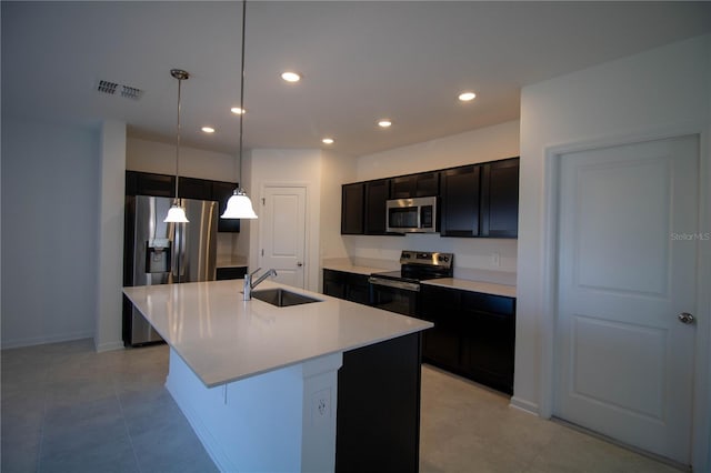 kitchen featuring appliances with stainless steel finishes, a kitchen breakfast bar, sink, a center island with sink, and hanging light fixtures