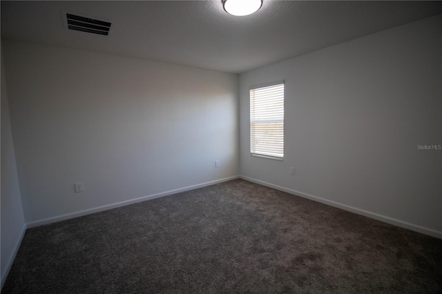 spare room with dark carpet