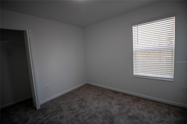 unfurnished bedroom featuring dark carpet and a closet