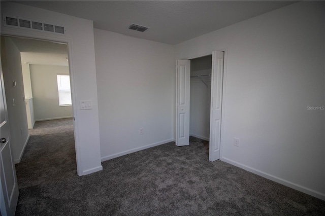 unfurnished bedroom with dark carpet and a closet