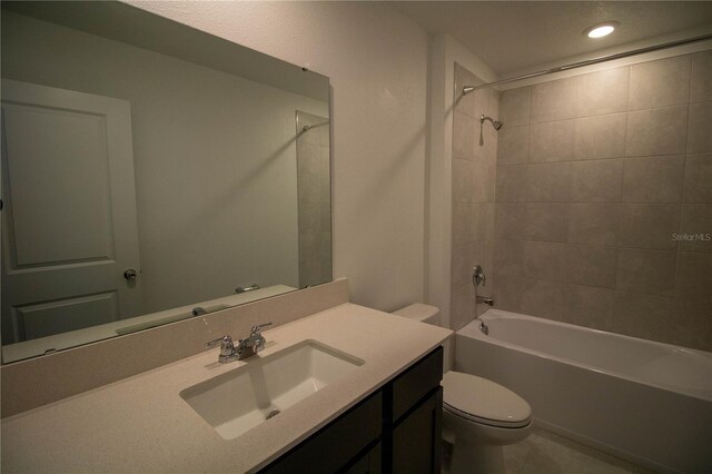 full bathroom featuring tile patterned flooring, vanity, tiled shower / bath combo, and toilet