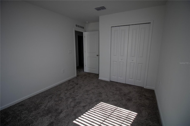 unfurnished bedroom featuring dark colored carpet and a closet