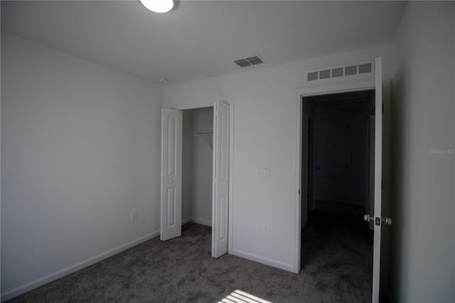 unfurnished bedroom with dark carpet and a closet