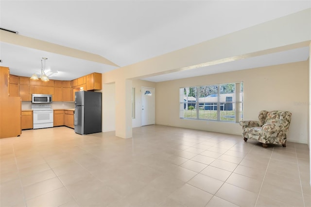 kitchen featuring appliances with stainless steel finishes, light tile patterned floors, pendant lighting, an inviting chandelier, and lofted ceiling