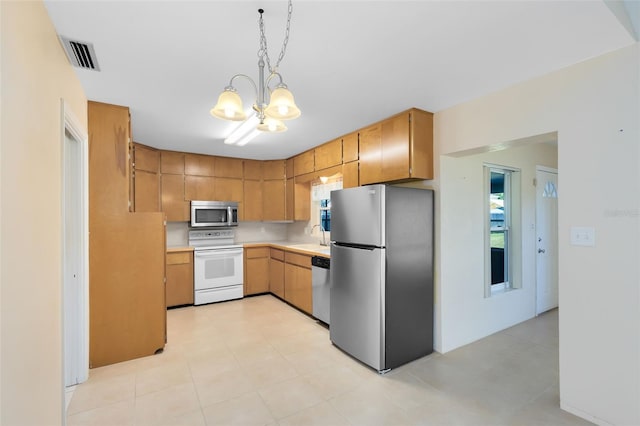 kitchen featuring appliances with stainless steel finishes, pendant lighting, sink, an inviting chandelier, and backsplash