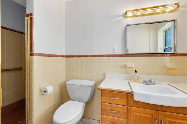 bathroom with toilet, vanity, tile walls, and a shower with shower door