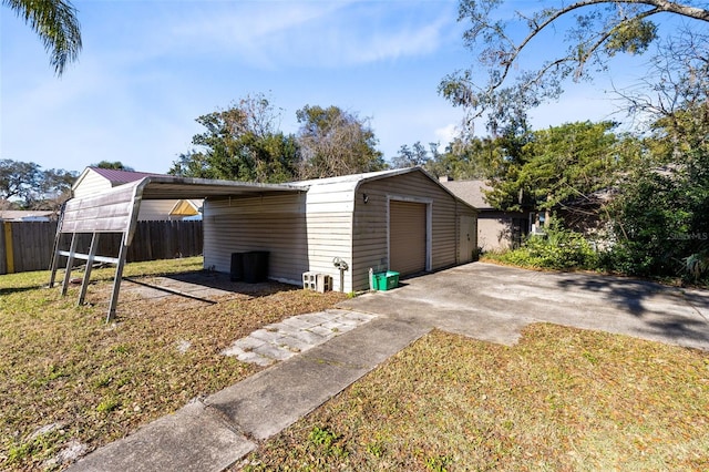 view of outbuilding featuring a garage, a lawn, and a carport