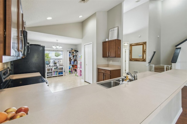 kitchen featuring lofted ceiling, sink, hanging light fixtures, a chandelier, and range