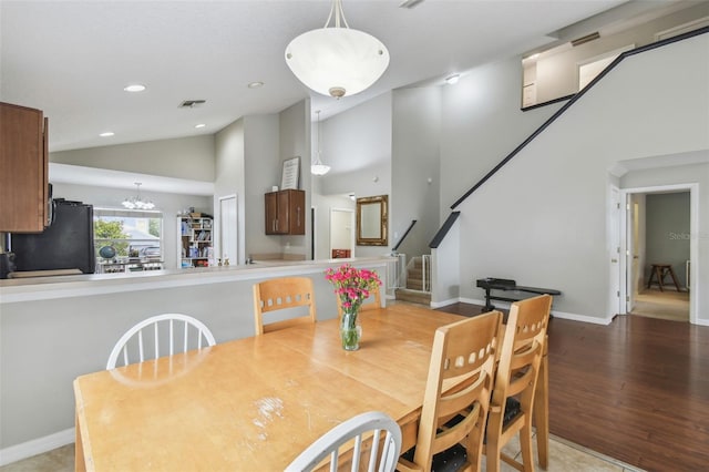 dining room featuring high vaulted ceiling, wood-type flooring, and an inviting chandelier