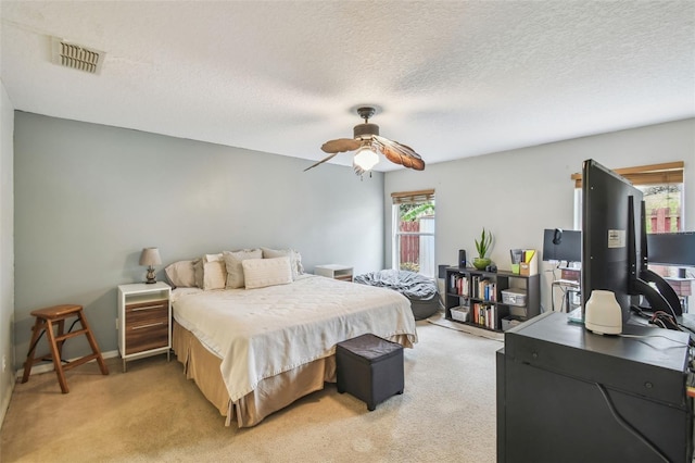 bedroom featuring ceiling fan, light colored carpet, and a textured ceiling