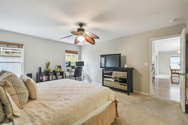 bedroom with ceiling fan, a textured ceiling, and light carpet