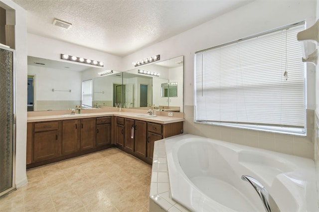 bathroom with a textured ceiling, independent shower and bath, and vanity