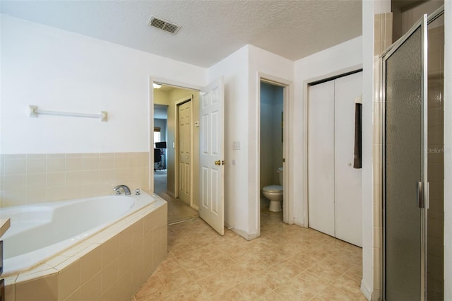 bathroom featuring tile patterned floors, a textured ceiling, toilet, and independent shower and bath