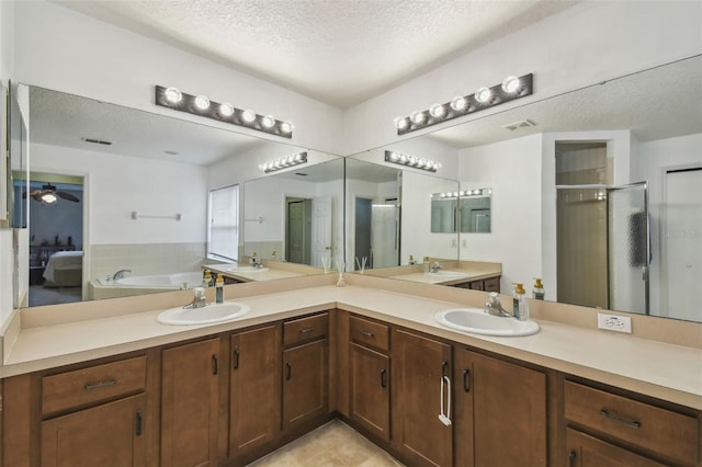 bathroom with a textured ceiling, ceiling fan, separate shower and tub, and vanity