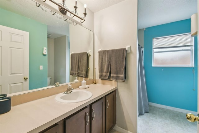 bathroom featuring a textured ceiling, toilet, vanity, and a chandelier