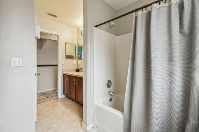 bathroom with vanity, shower / tub combo with curtain, and a textured ceiling