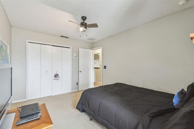 bedroom with ceiling fan, a textured ceiling, a closet, and light carpet