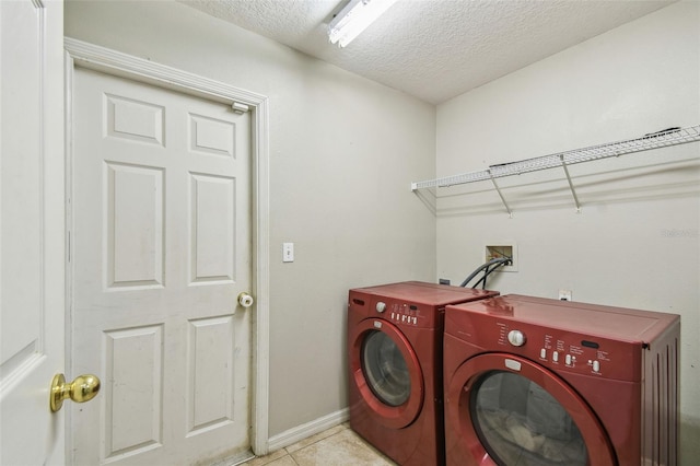 clothes washing area with a textured ceiling, light tile patterned floors, and independent washer and dryer