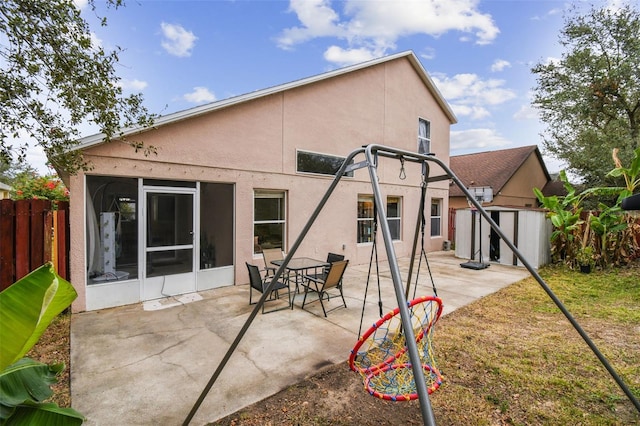 rear view of property with a storage unit, a patio area, and a sunroom