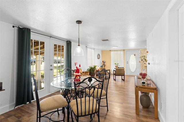 dining space featuring french doors, a textured ceiling, and hardwood / wood-style flooring