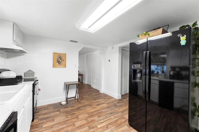 kitchen featuring black appliances, white cabinetry, sink, and hardwood / wood-style flooring