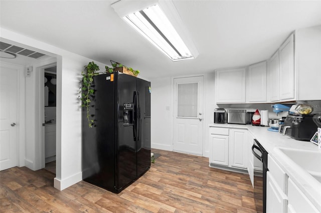 kitchen with sink, white cabinets, black appliances, and dark hardwood / wood-style floors