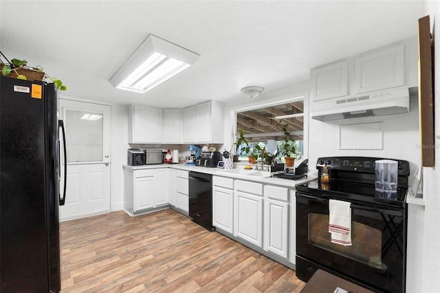 kitchen with black appliances, white cabinets, sink, light hardwood / wood-style flooring, and range hood