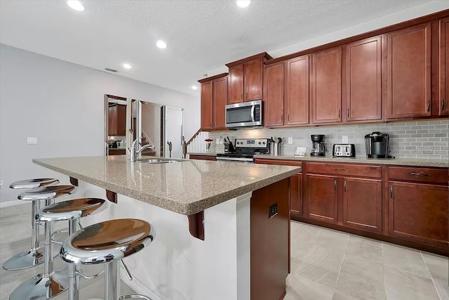 kitchen with appliances with stainless steel finishes, a kitchen island with sink, and sink