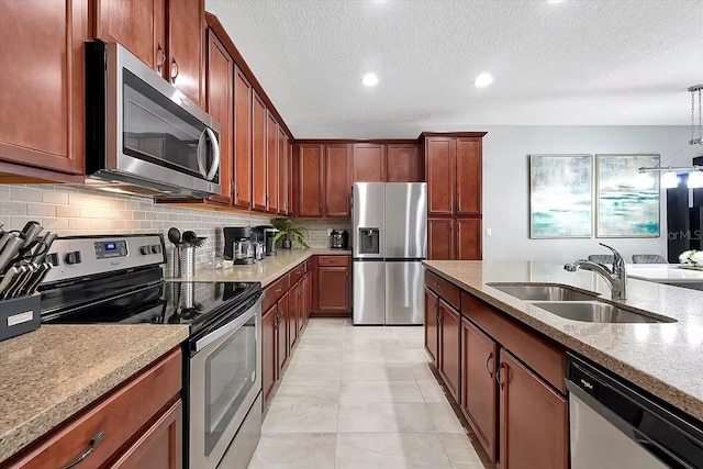 kitchen with pendant lighting, sink, tasteful backsplash, light tile patterned flooring, and stainless steel appliances