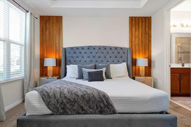 bedroom with carpet flooring, connected bathroom, and a tray ceiling