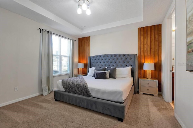 bedroom featuring light colored carpet and a raised ceiling