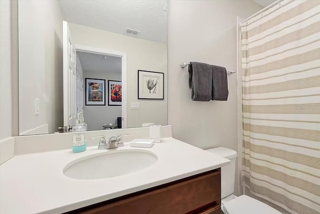 bathroom with vanity, a textured ceiling, and toilet