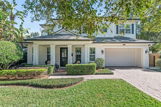 view of front of house featuring covered porch, a front yard, and a garage