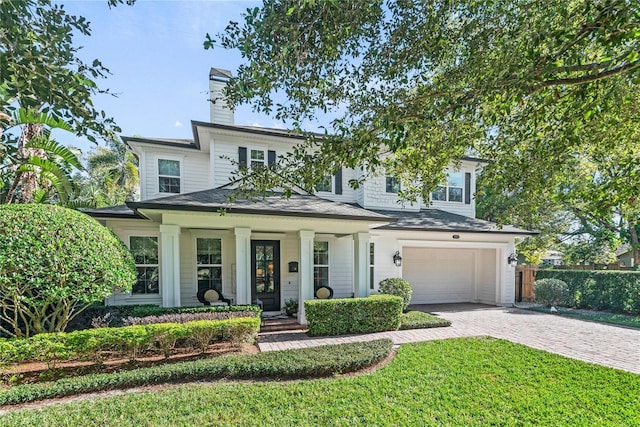 view of front of home featuring a porch, a garage, and a front lawn