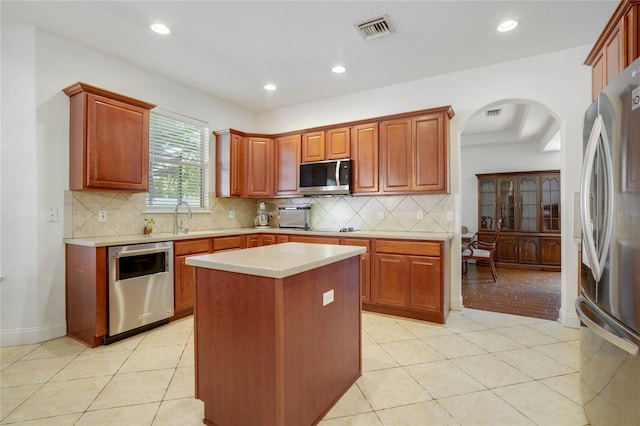 kitchen with tasteful backsplash, a kitchen island, light tile patterned floors, and appliances with stainless steel finishes