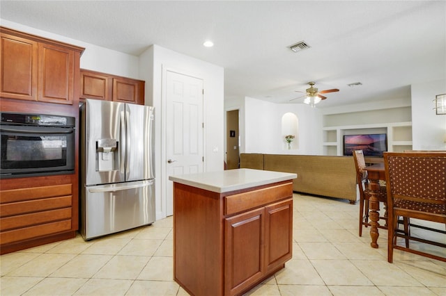 kitchen featuring stainless steel fridge, built in shelves, light tile patterned floors, oven, and a kitchen island